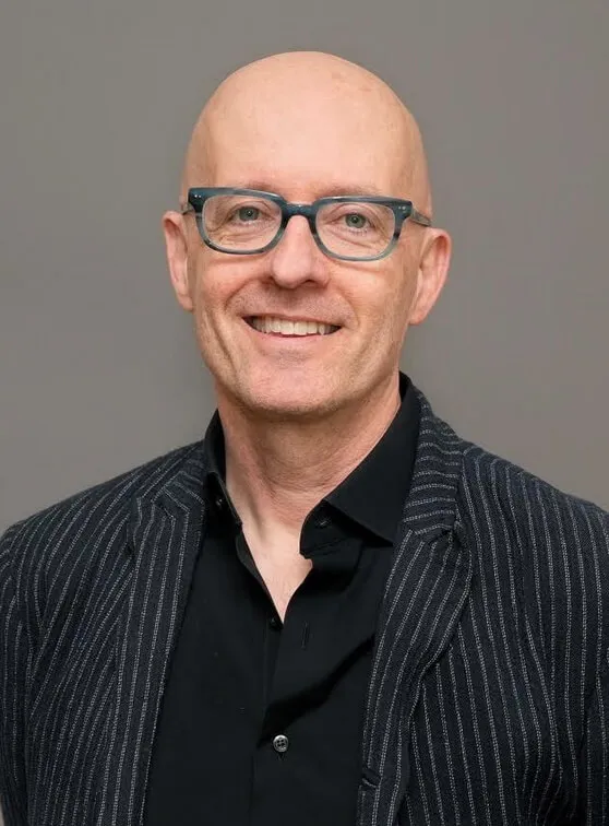 Headshot of a man in a suit with glasses