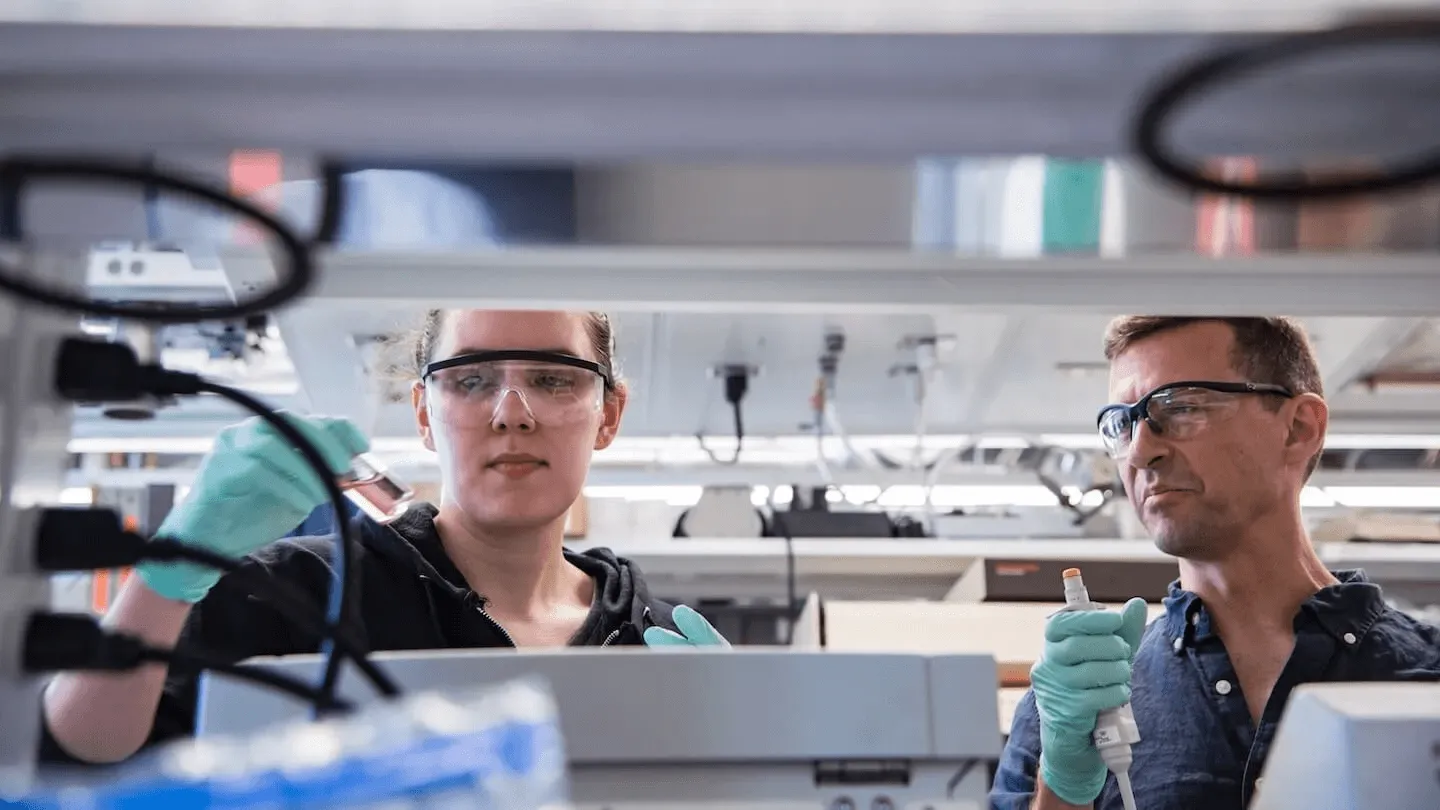 two lab workers seen at a lab bench
