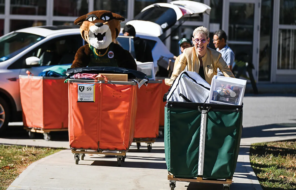 marlene pushes a green cart while racing the uvm mascot rally cat
