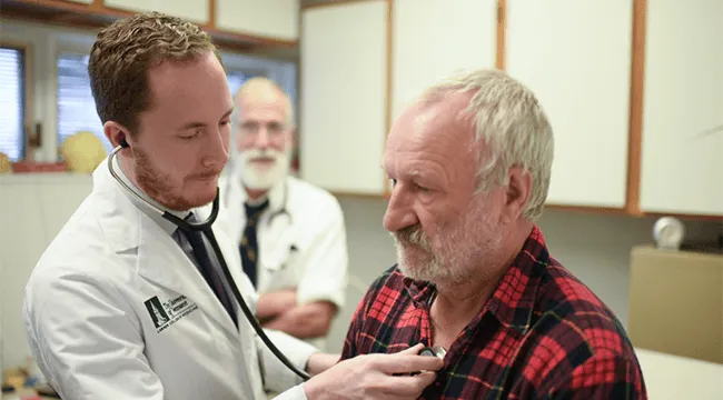 2 doctors with a patient in an exam room