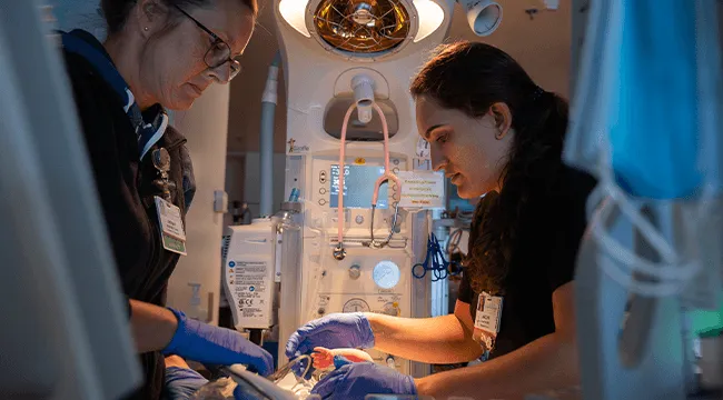 2 people treating a baby in a NICU