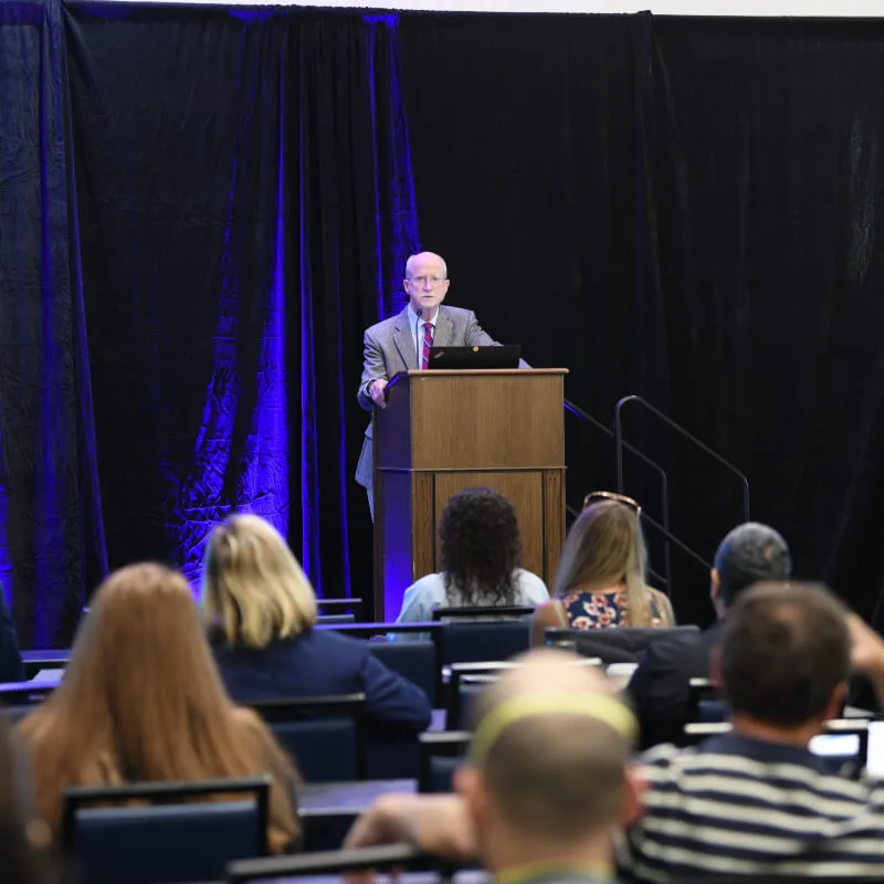 person at lecturn speaking to audience