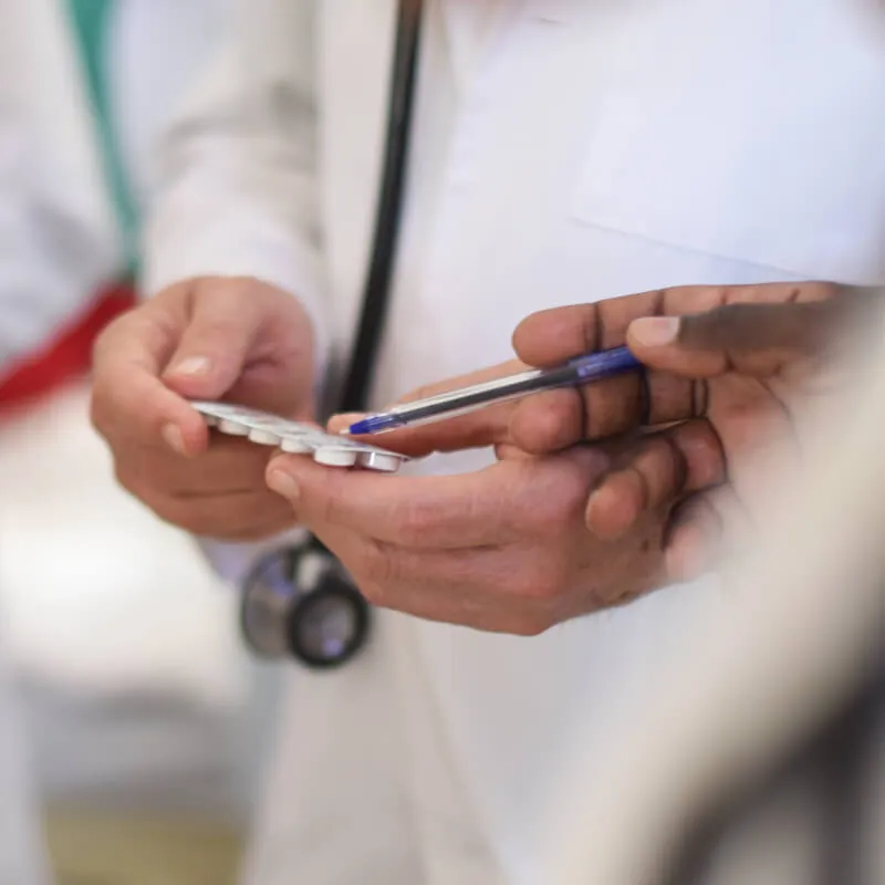 close up of hands holding medication while another points a pen