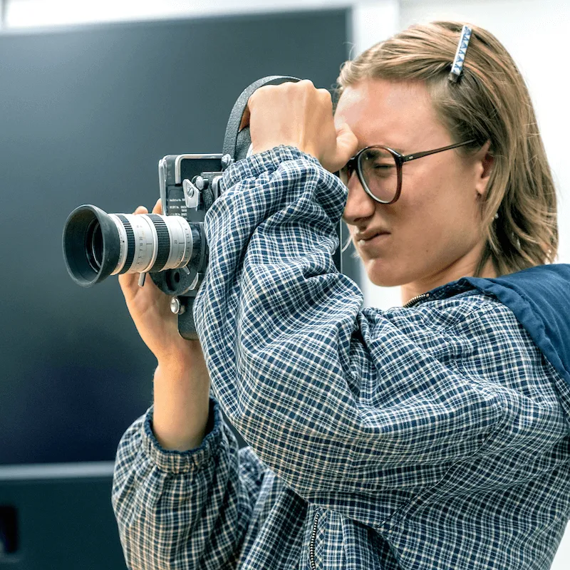 Person looking through the viewfinder of a vintage film camera.