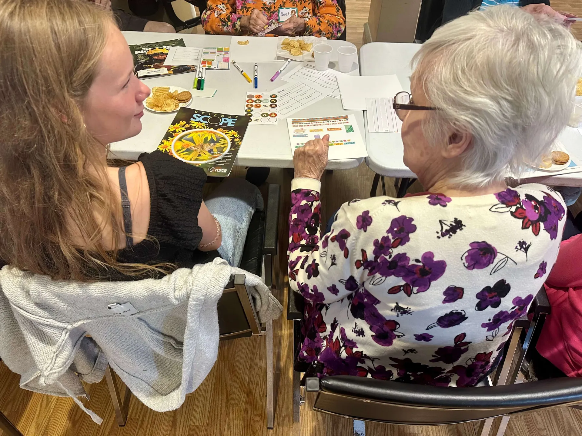 An older woman and a teen sitting next to each other while making collages