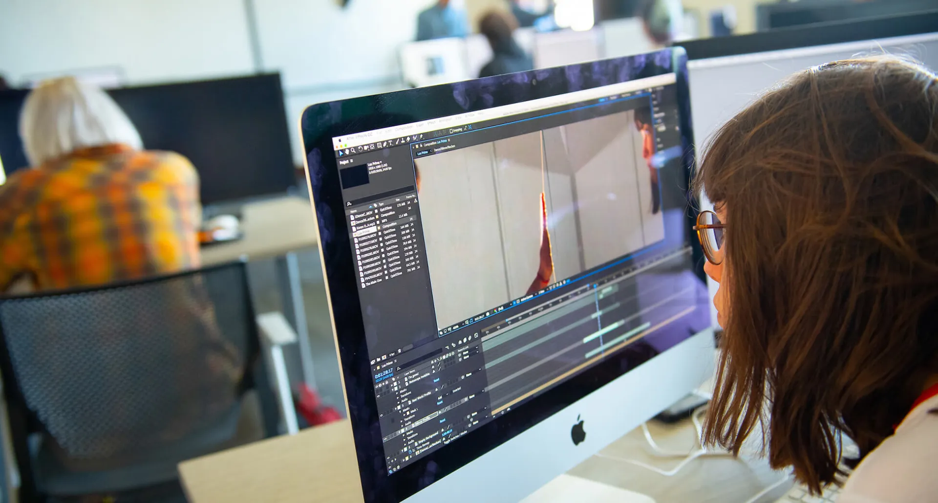 Person editing video on a computer in a classroom.