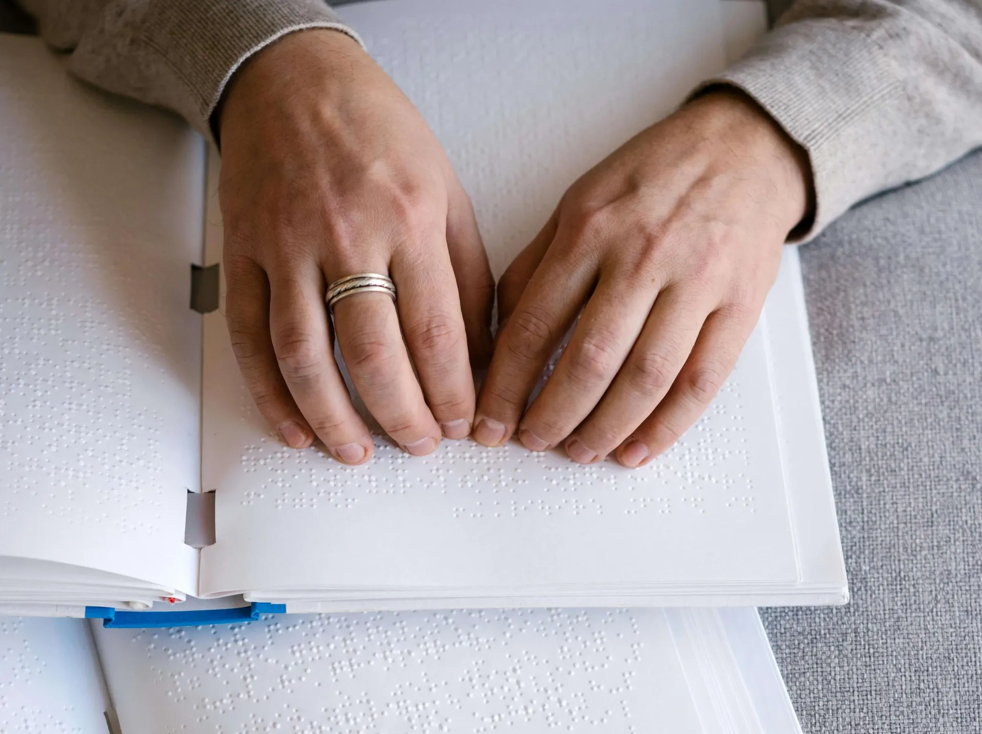 Hands reading an open Braille book