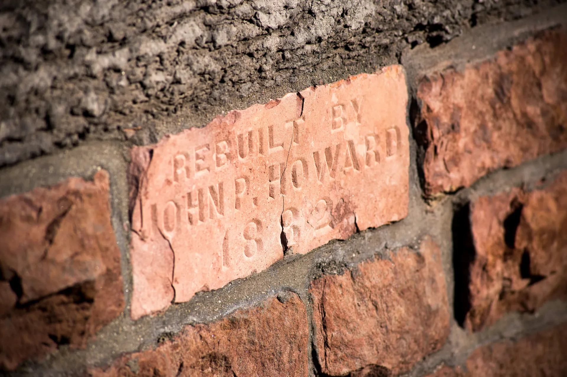 Close-up of a stamped brick reading “Rebuilt by John P. Howard 1882” in UVM Old Mill.