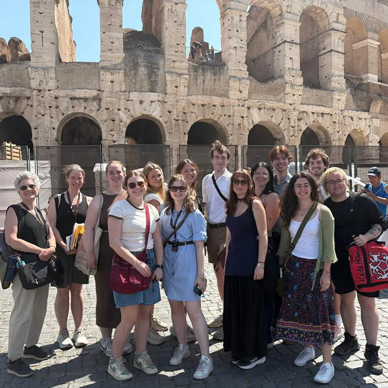 Group of students standing together in front of the Colosseum in Rome.