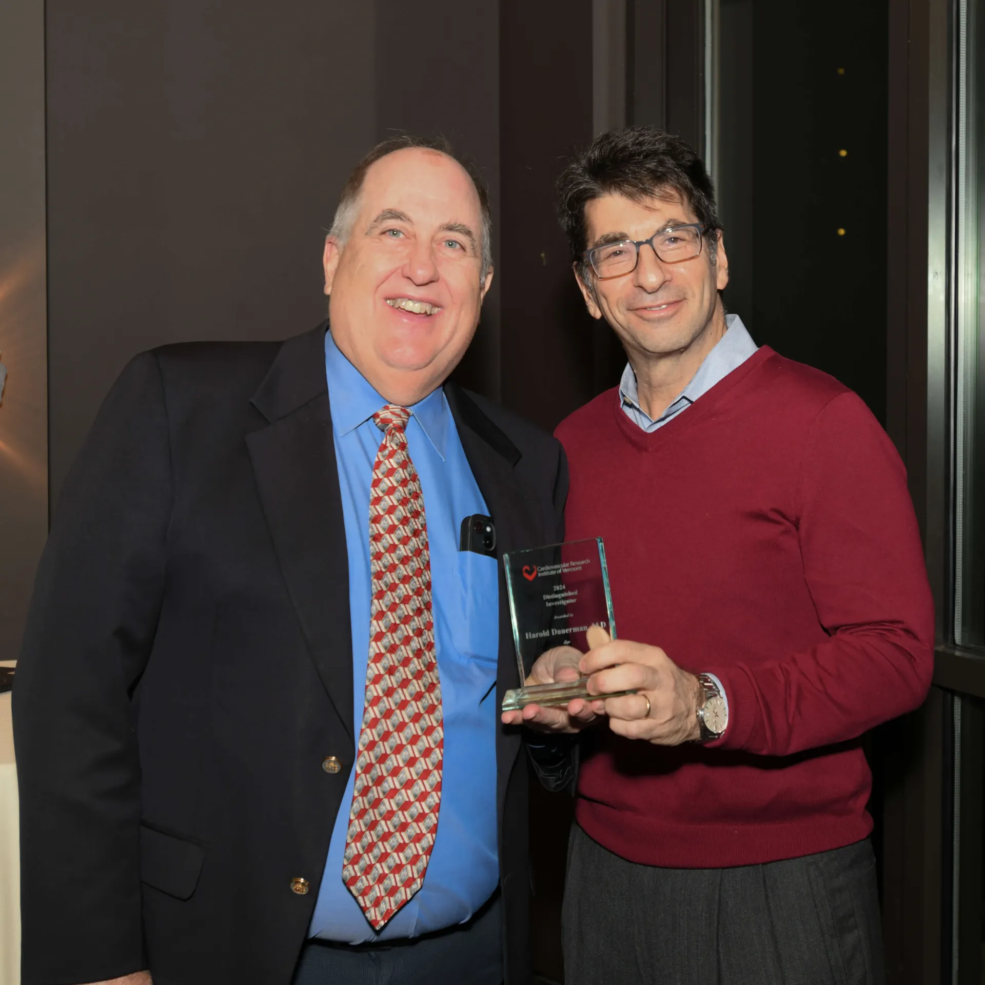Two men holding award plaque 