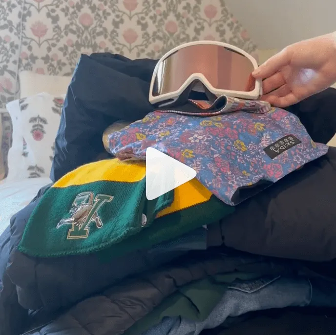 Layers of clothing are tossed into a pile on a bed. 