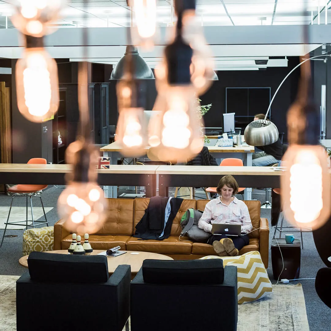 a student sits in a coworking space surrounded by Edison lights