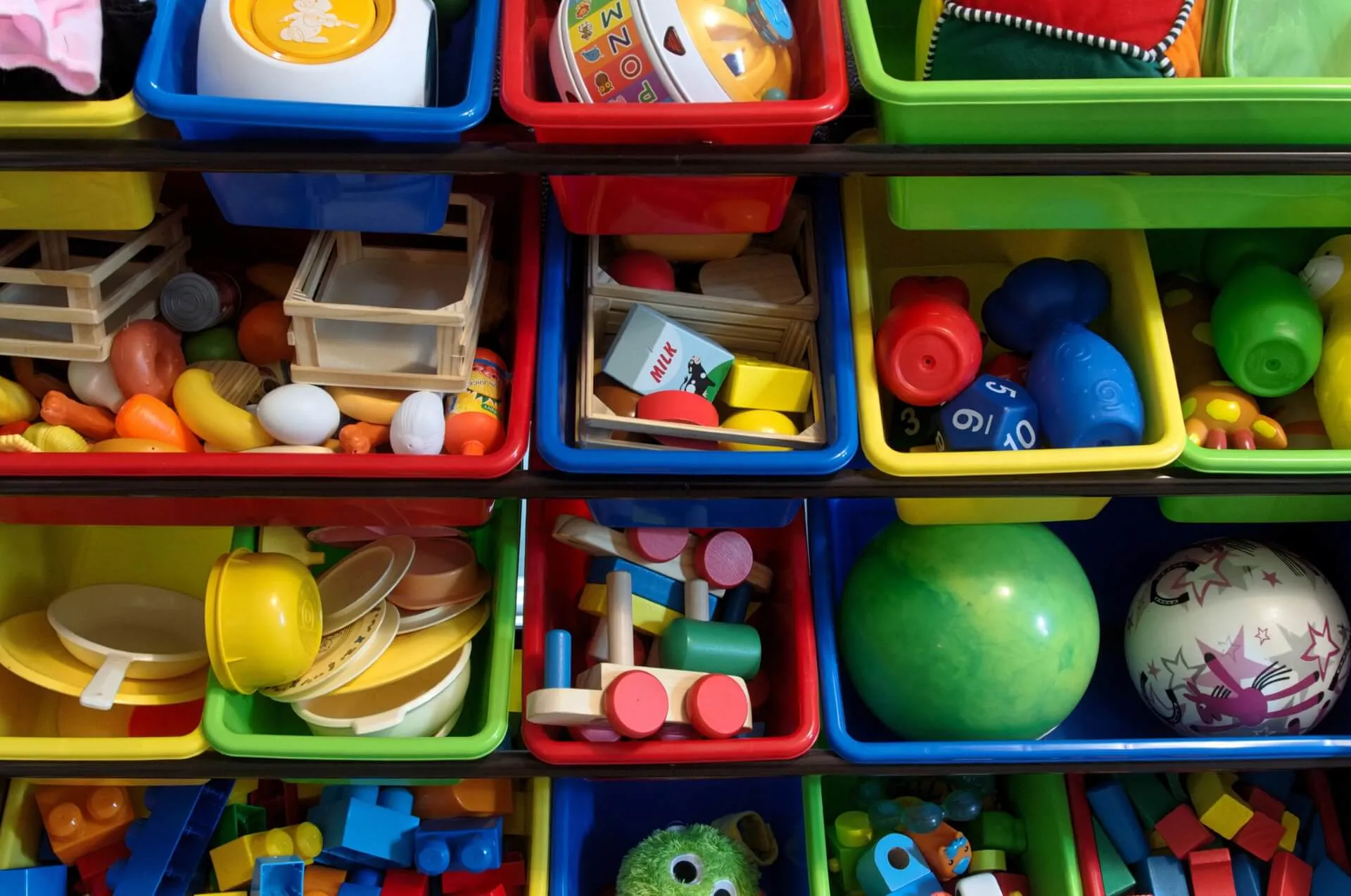 A photo of a shelf of plastic bins filled with children's toys