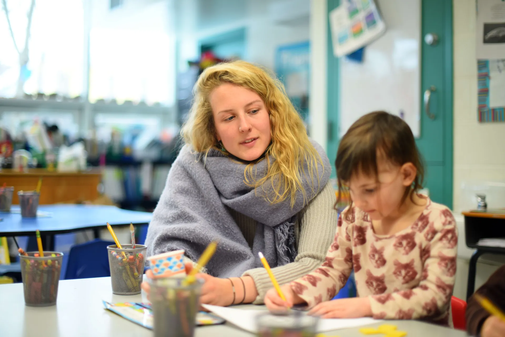 Woman working at table with young student.