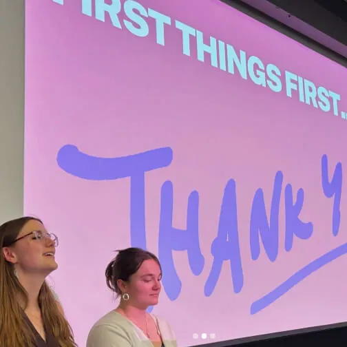 Two presenters stand in front of a projected slide that reads “Thank You.”