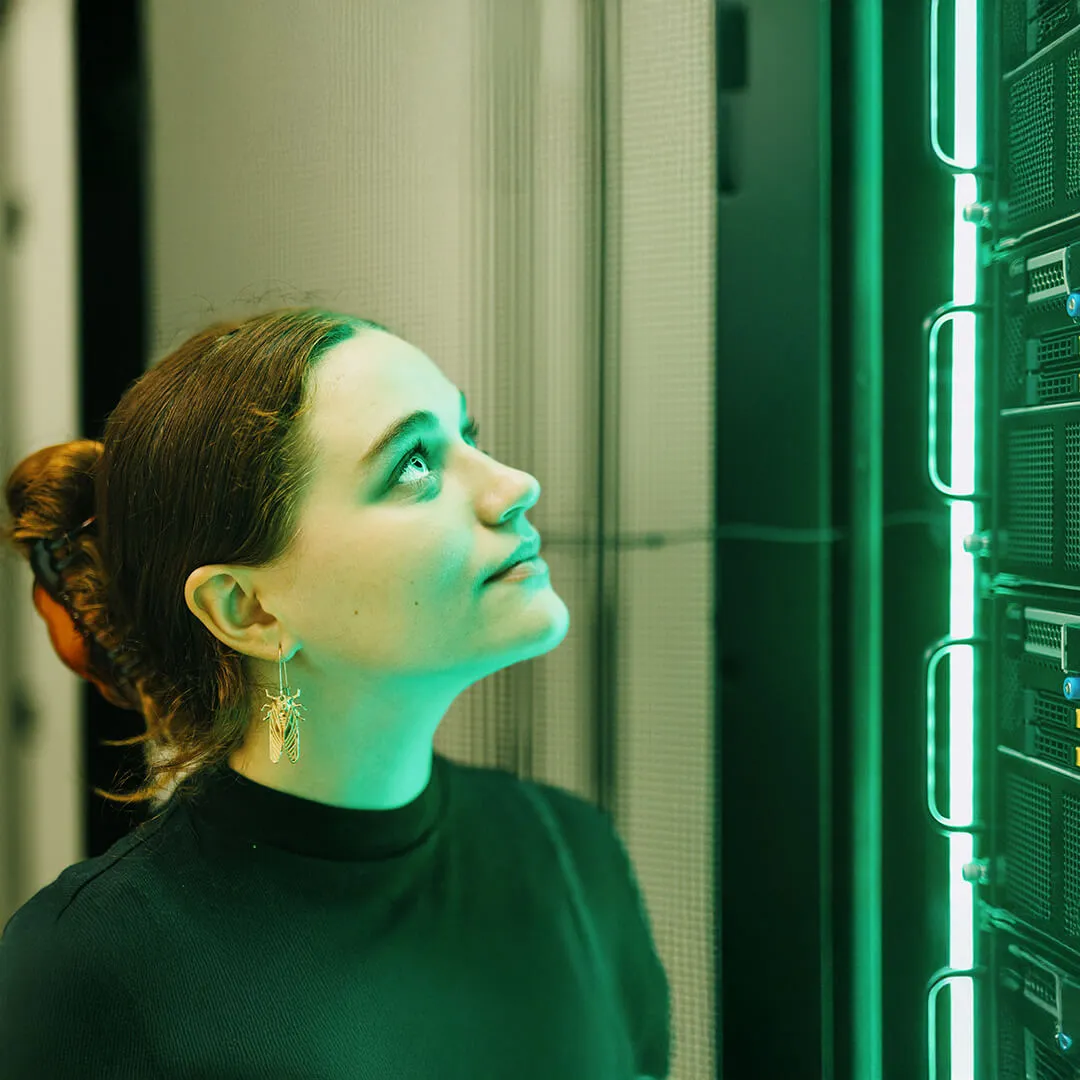 a student looks up at a green lit computing core