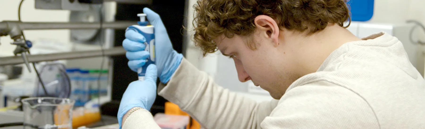 Graduate student using a pipette in a laboratory.