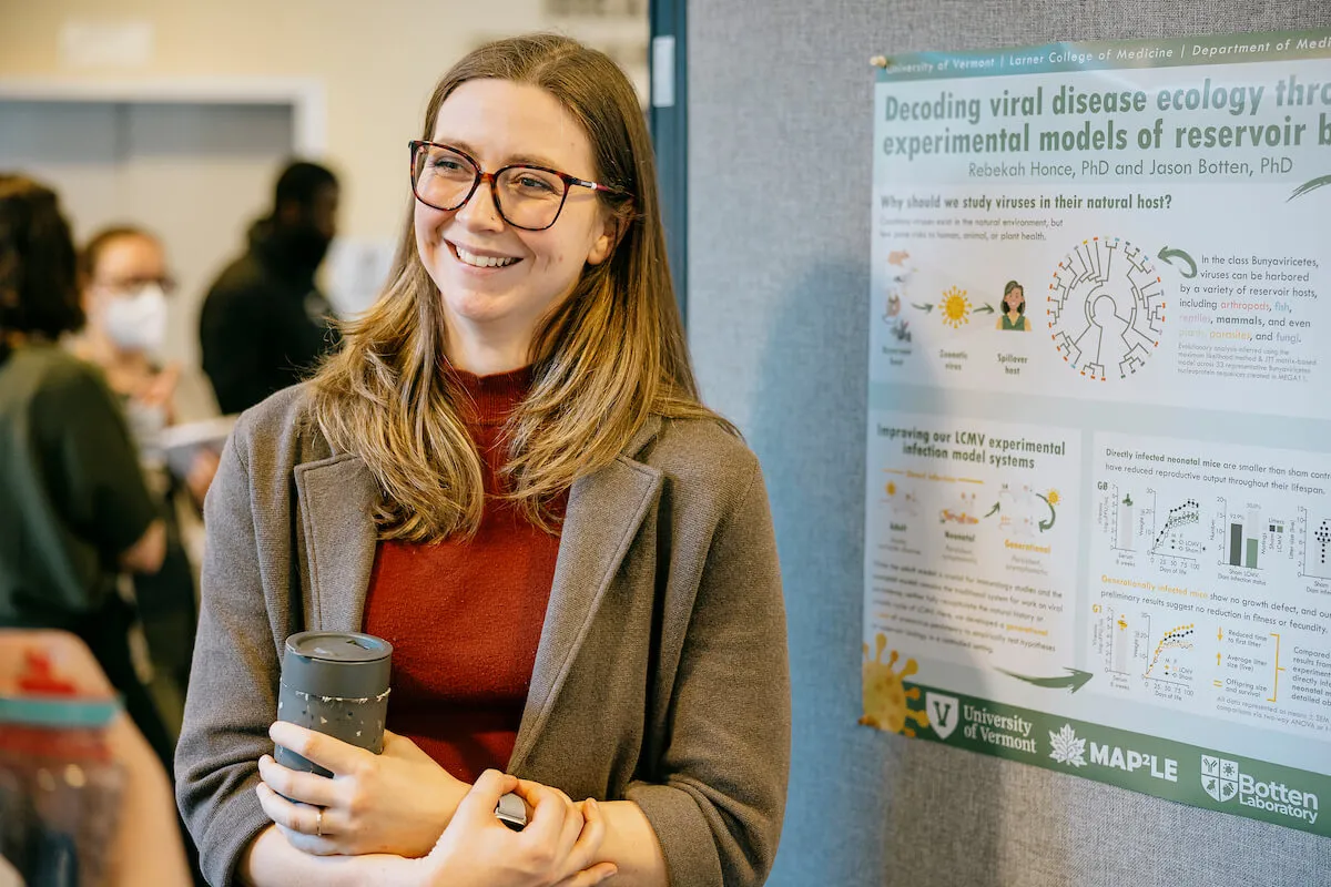 A postdoctoral student stands in front of their research findings
