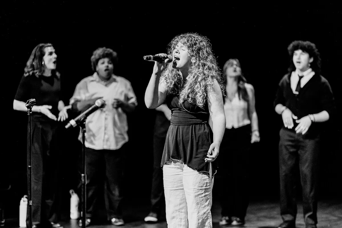 A group of students sing on stage