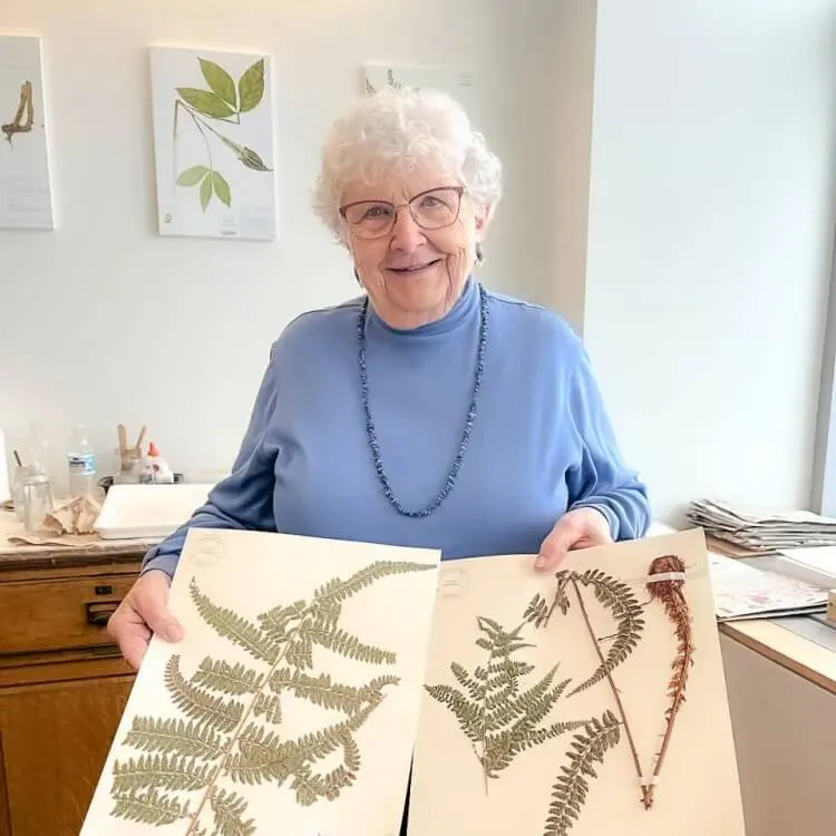 Hilda displaying mounted specimens of a large fern