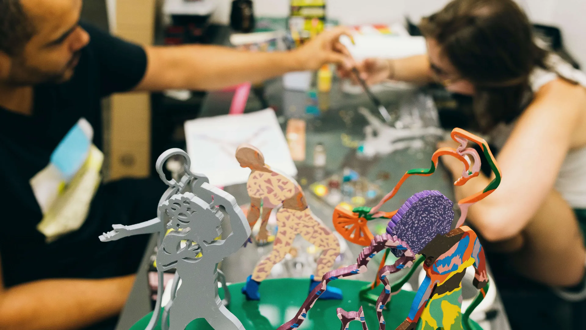 Two people work on paintings and sculptures