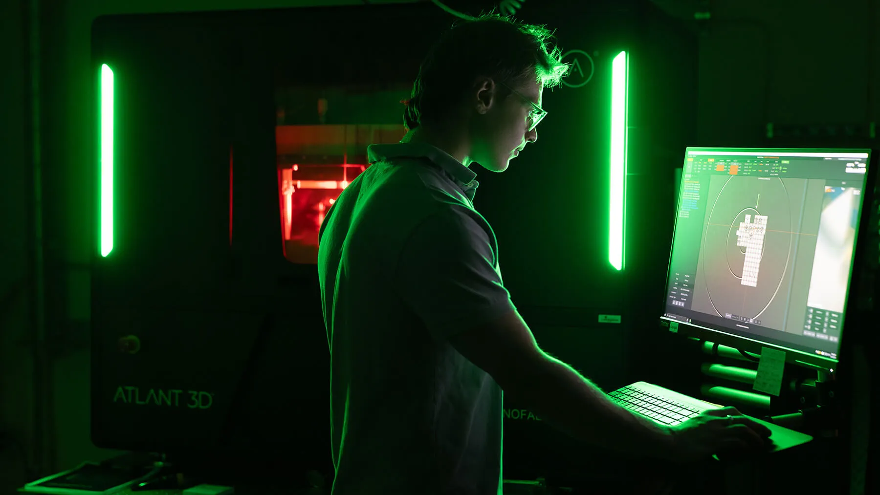 A photo of a darkened lab with a student working at a computer station