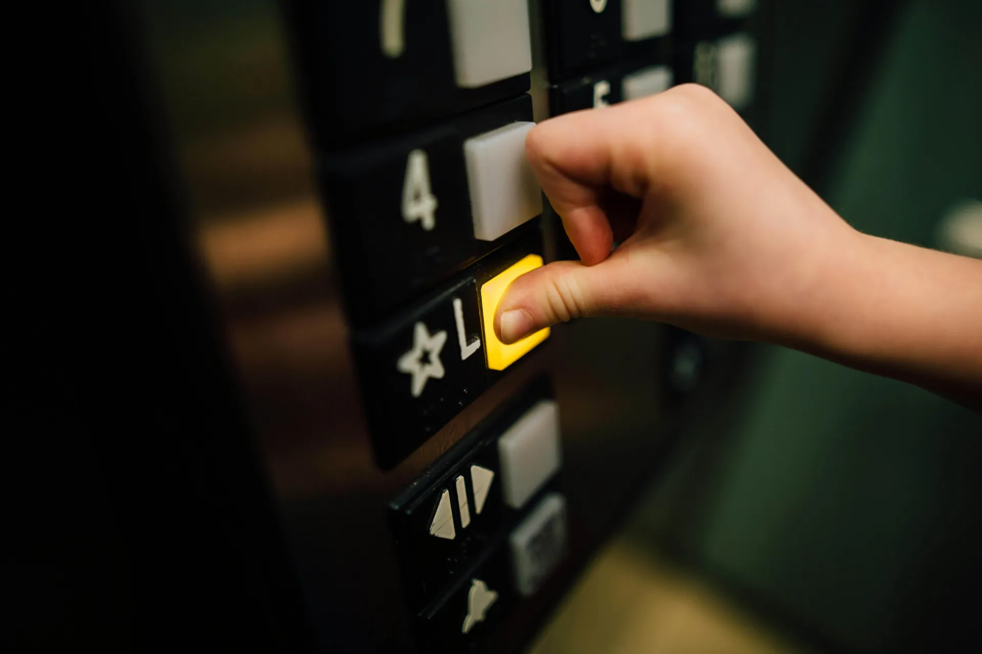 A hand pressing an elevator button for the lobby