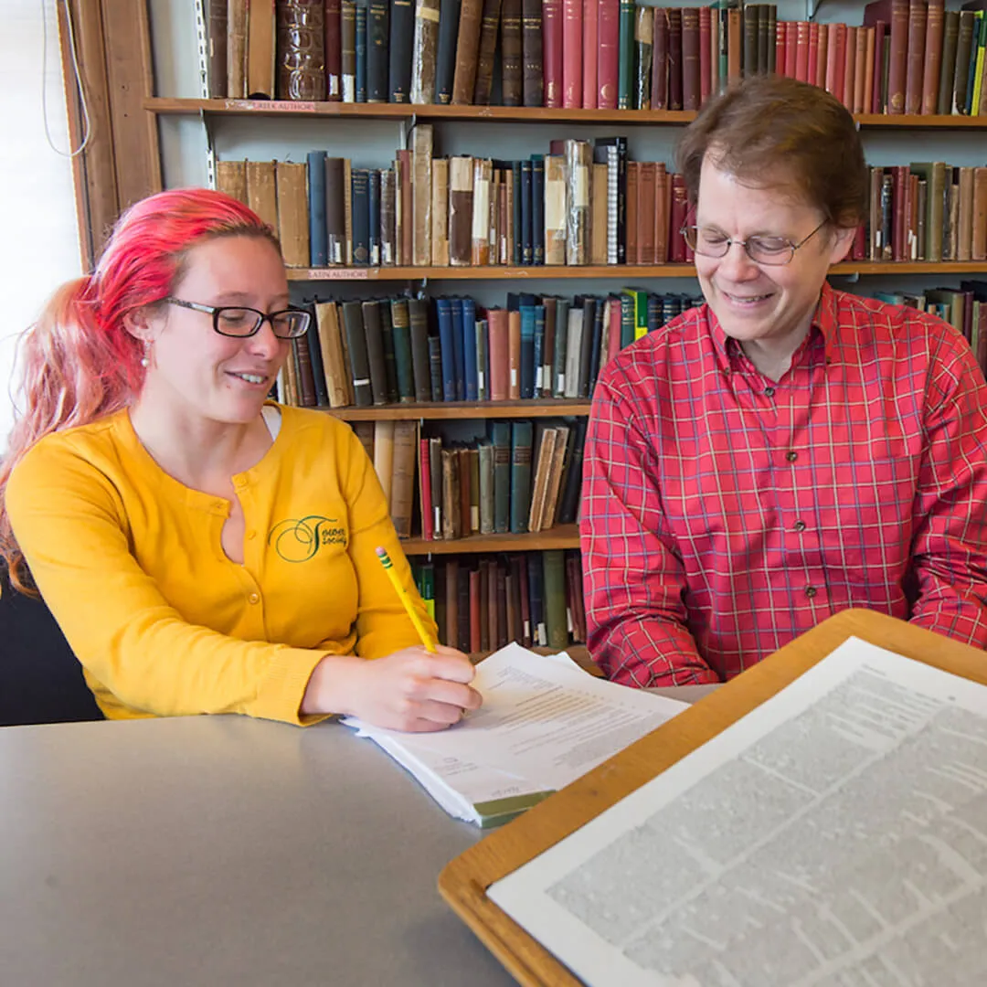 Two people reviewing a document together at a table in a library.