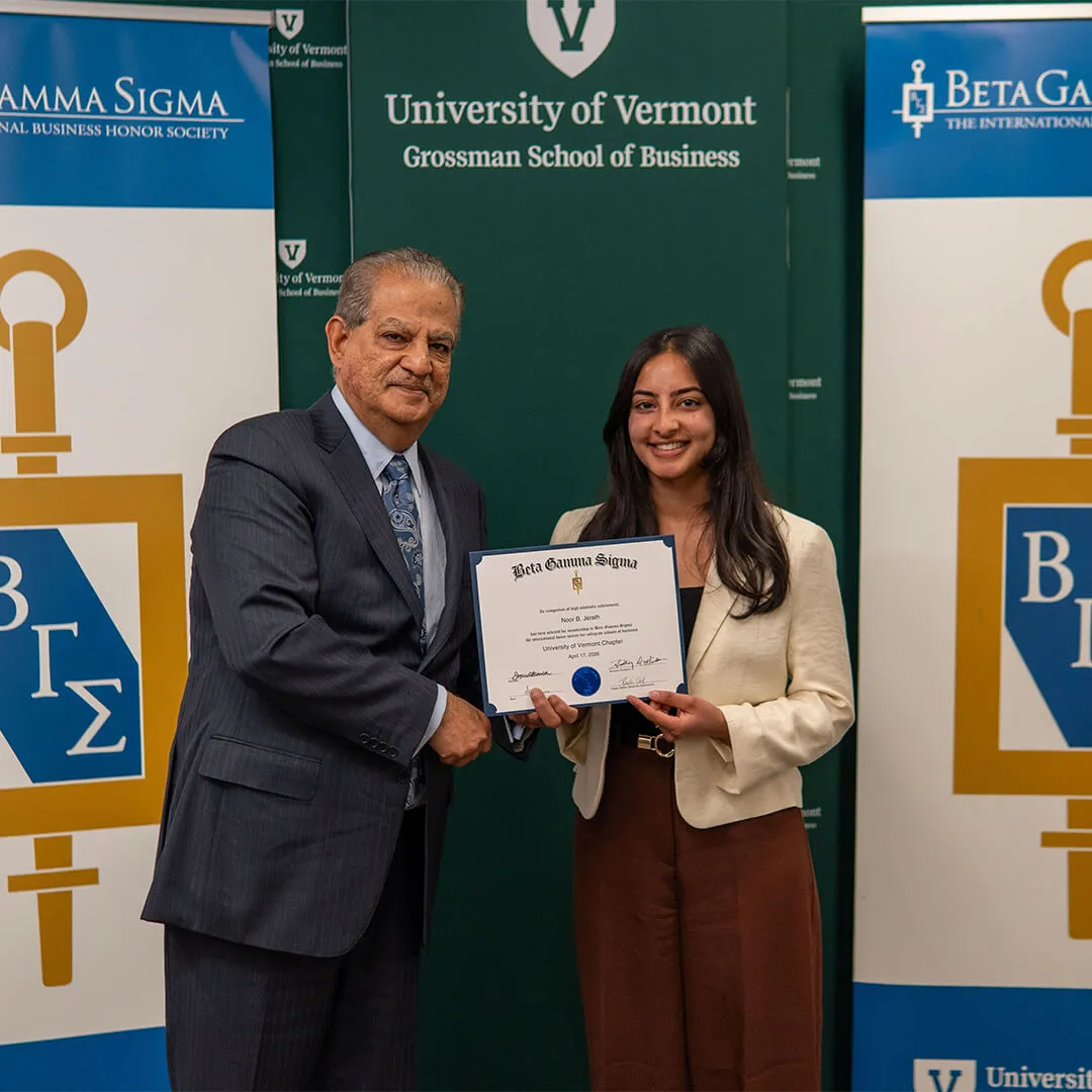 A student is presented with their Beta Gamma Sigma certificate by Dean Sanjay Sharma