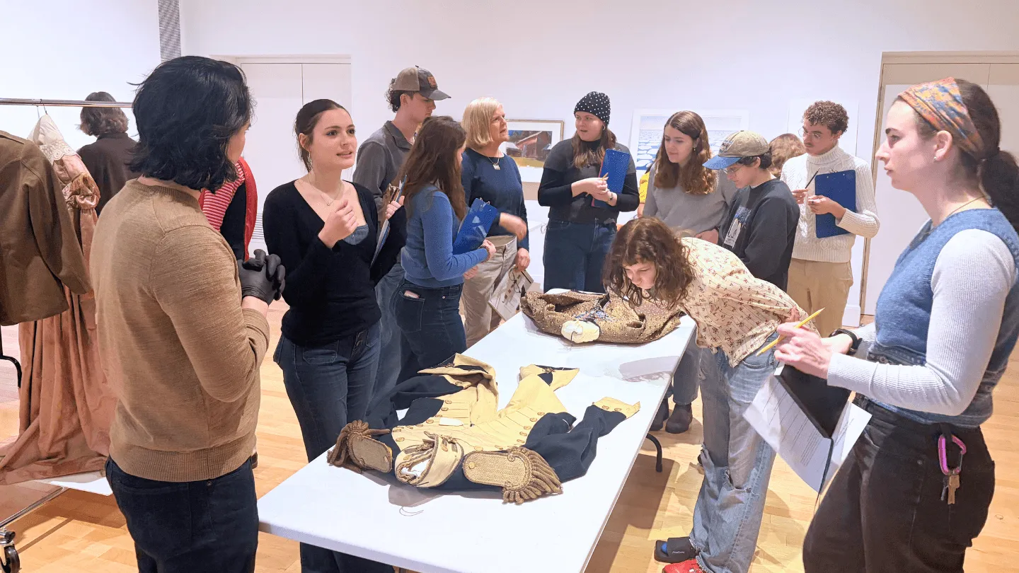 A group of students examine artwork on a table