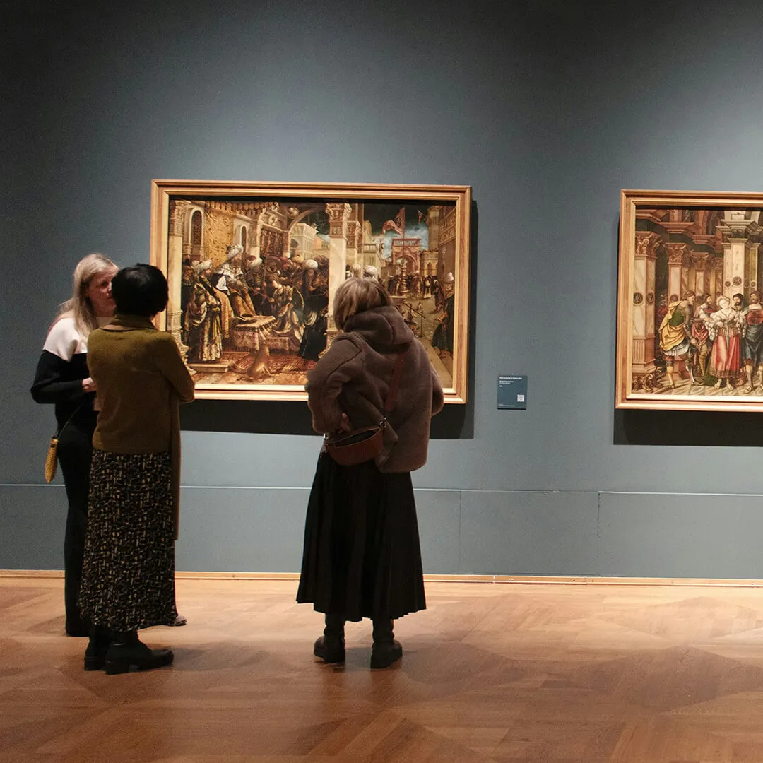 Visitors viewing paintings in a museum gallery.