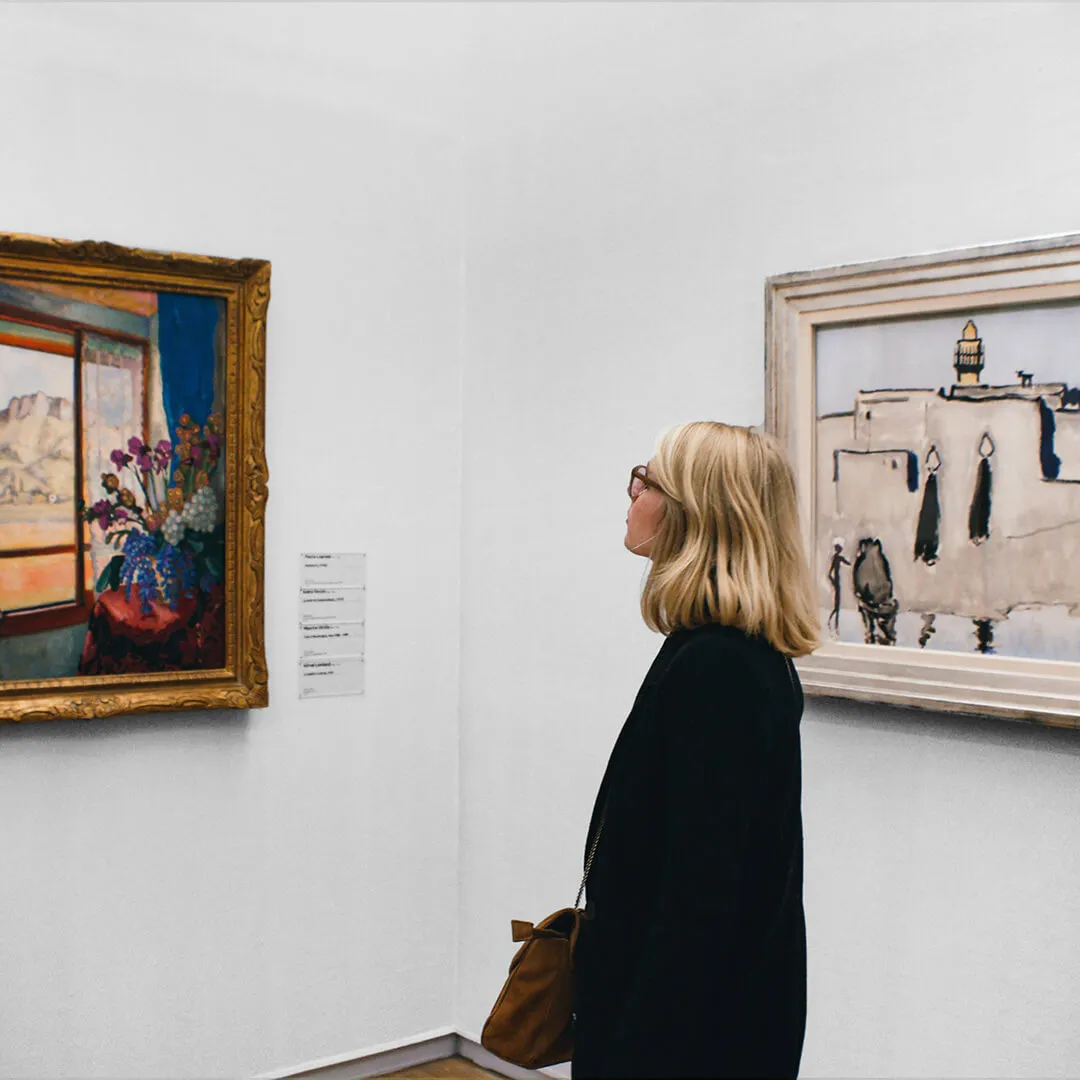Person viewing paintings in an art gallery.