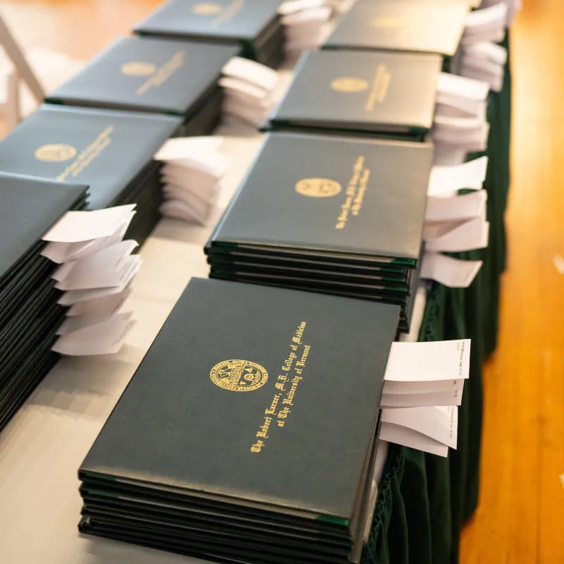 two rows of diplomas on a table with white tags sticking out of each one