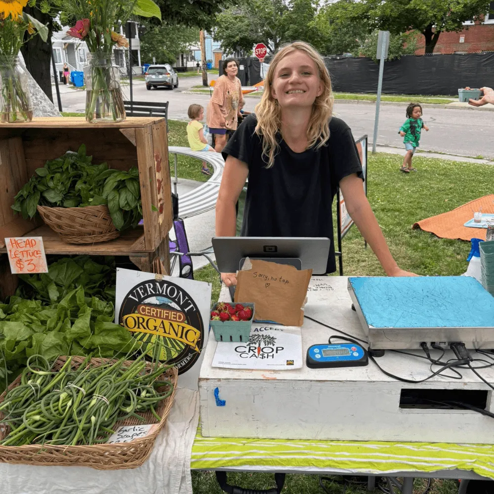 UVM Student selling produce at the farmers market