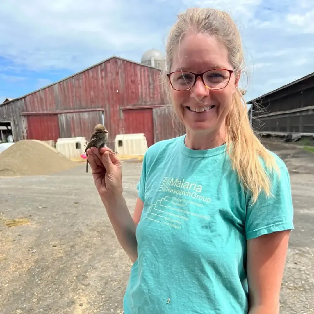 Dr Ellen Martinsen holding a bird by a barn