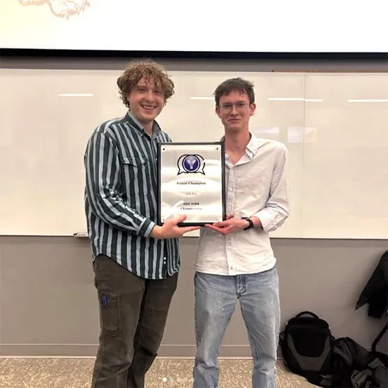 Two students holding a championship plaque after winning the YODL debate championship for UVM’s Lawrence Debate Union.