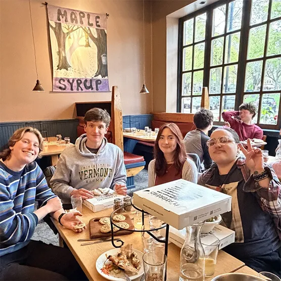 Students gathered around a table during a club meeting at UVM.