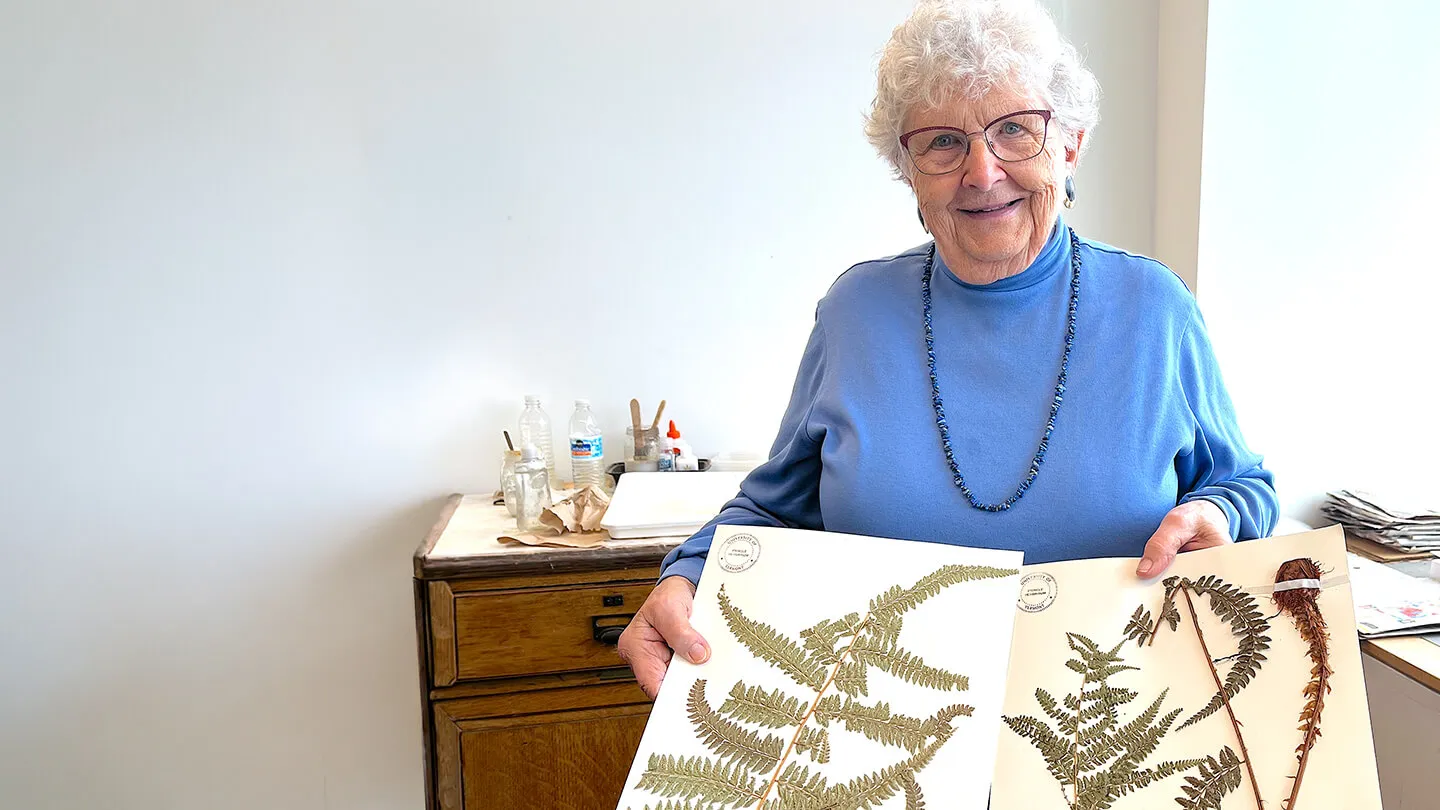 a woman holding sheets of pressed ferns