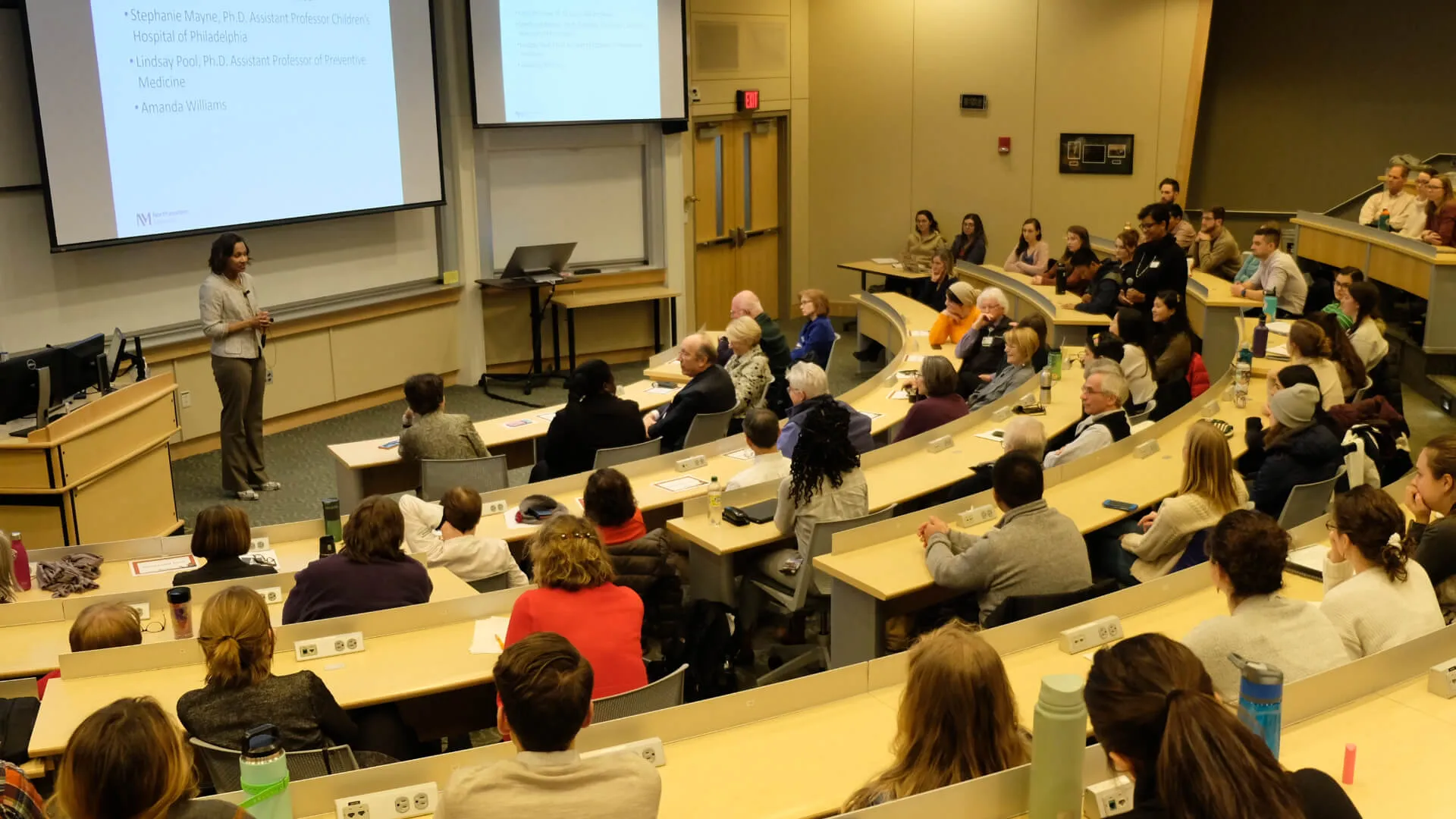 a well attended seminar in an auditorium setting with speaker at front of room