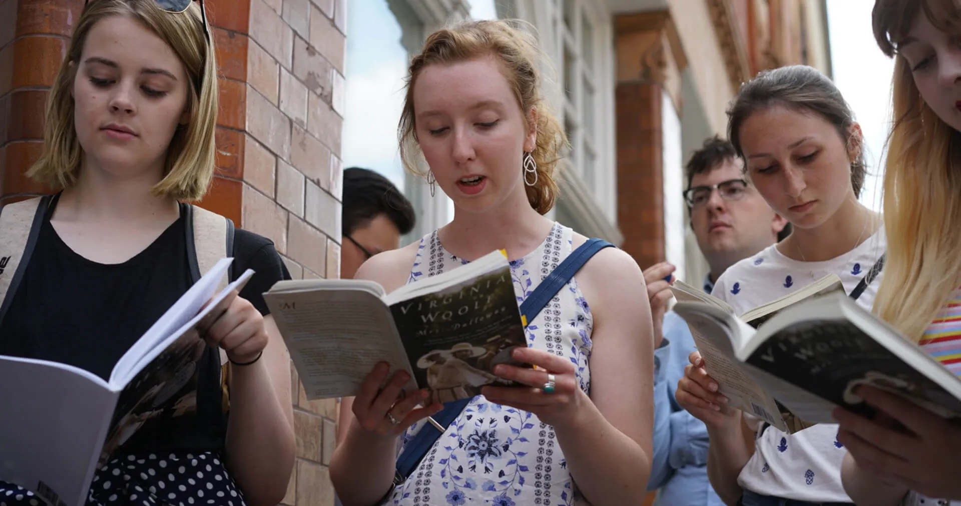 Group of people reading books together outdoors.