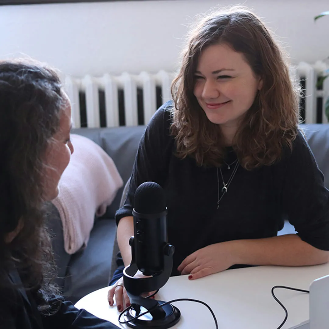 Two people speaking into a microphone during an interview.