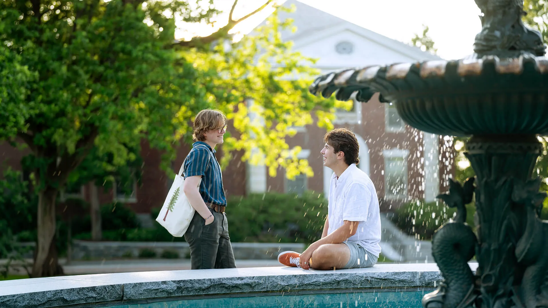 Two students chat by a fountain.