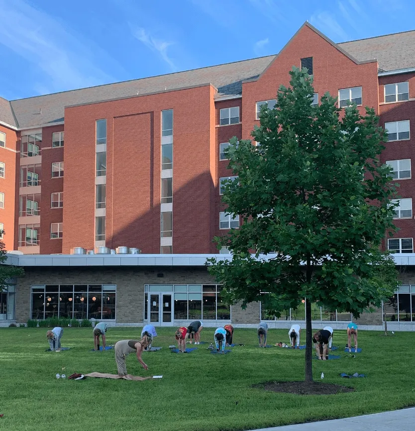 students doing yoga outside in front of a building