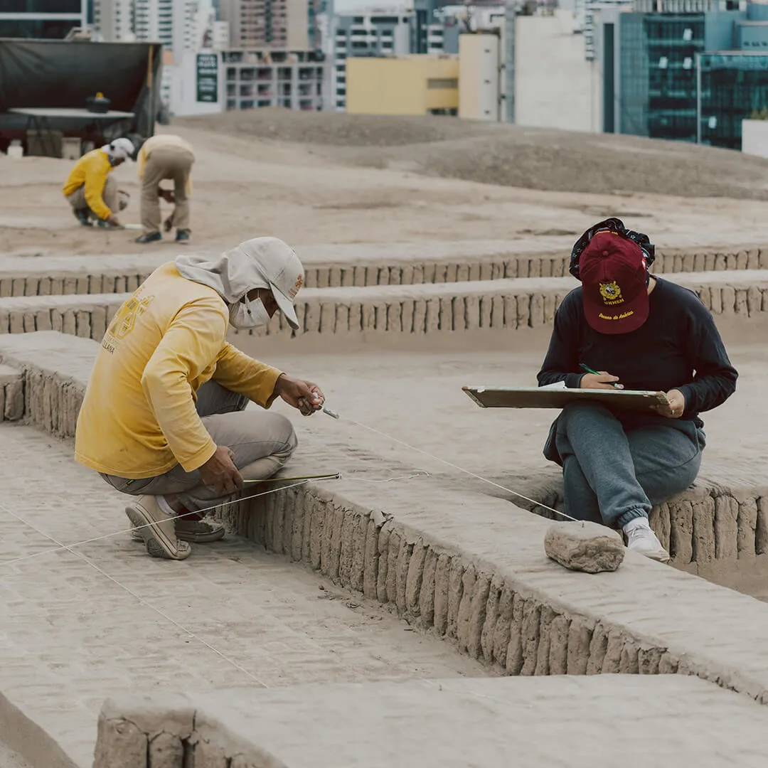 Archaeologists measuring and documenting an excavation site during field research.