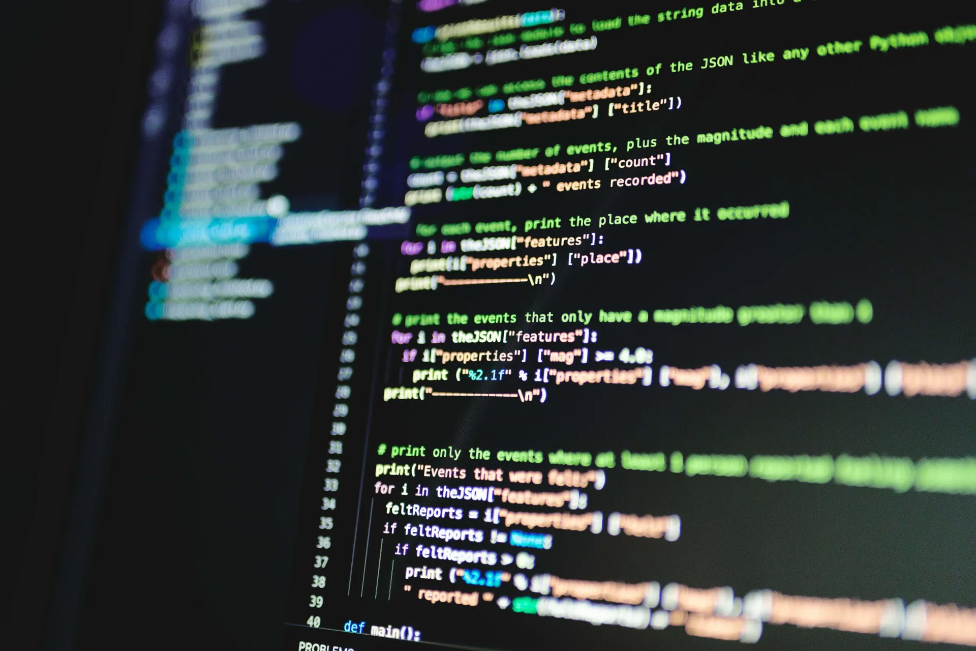 Close up of a computer monitor showing lines of code in neon colors against a dark background
