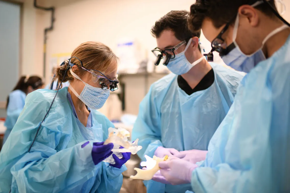 faculty and 2 students in the OR learning a procedure
