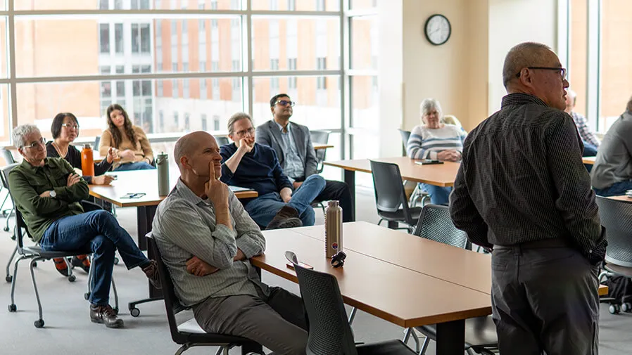 A group of faculty and students sit in a classroom and listen to a lecture as part of the Research Seminar Series