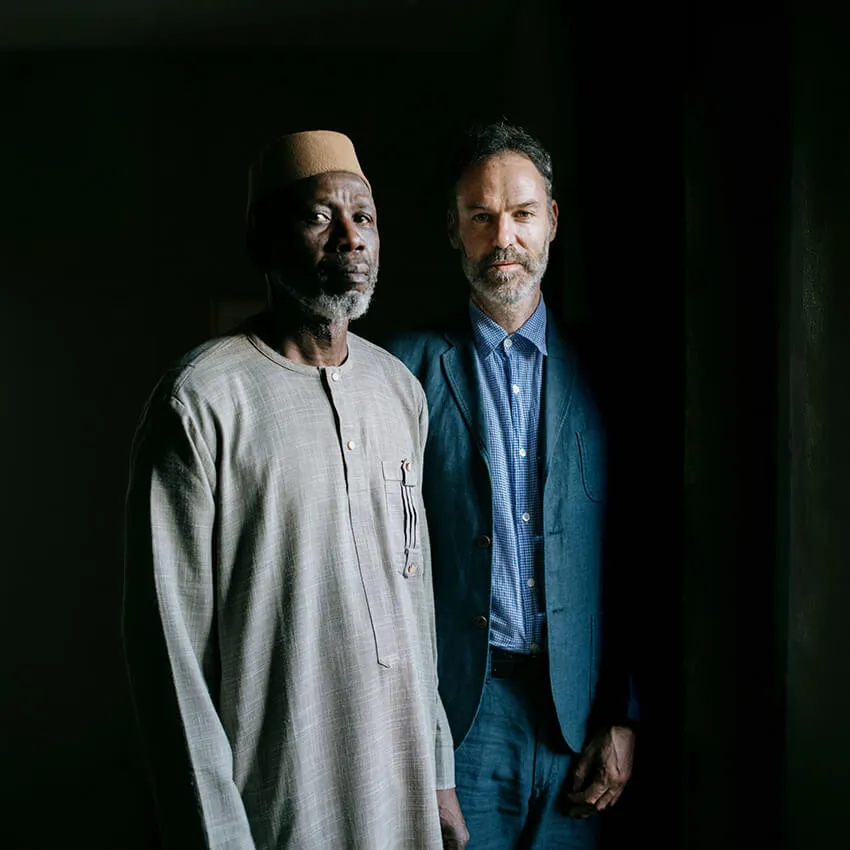 Two men standing in front of a black backgroun