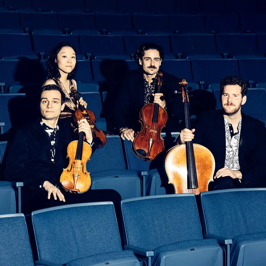 Four people sitting in theatre seats holding classical instruments