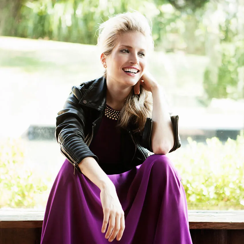 A woman in a leather jacket and a purple skirt
